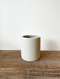 Indlæs billede i gallerivisning, Elegant lille betonkrukke i rå cement med dimensionerne Ø15 x H17 cm, perfekt til små planter som orkidéer og sukkulenter. Anvendelig både indendørs og udendørs.